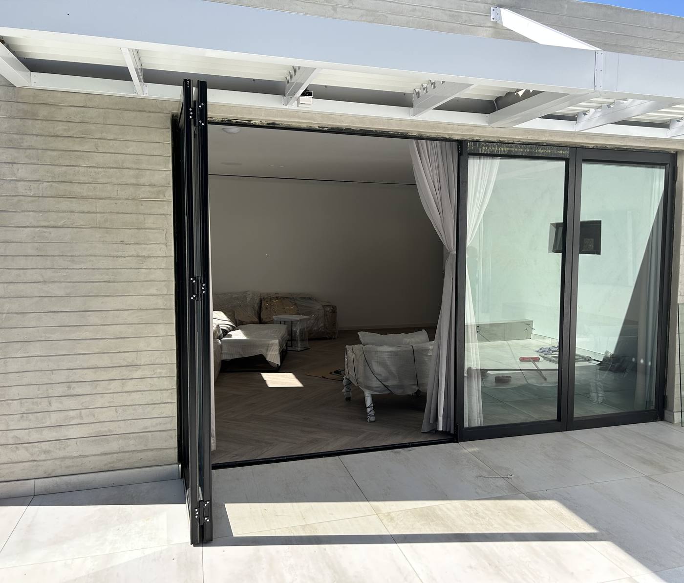 Black aluminium folding doors stacked open onto a terrace