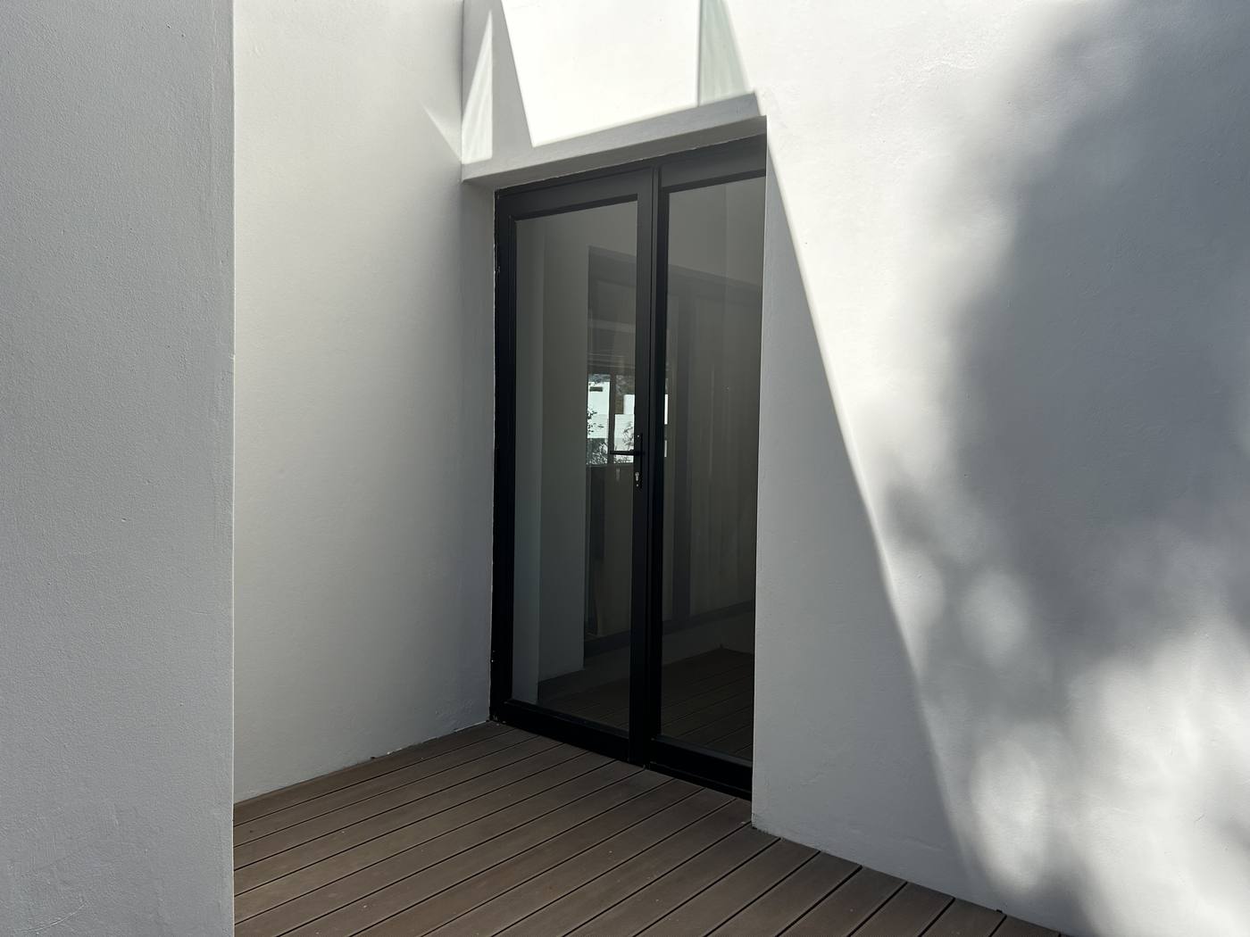 Black-framed hinged glass doors in a white courtyard