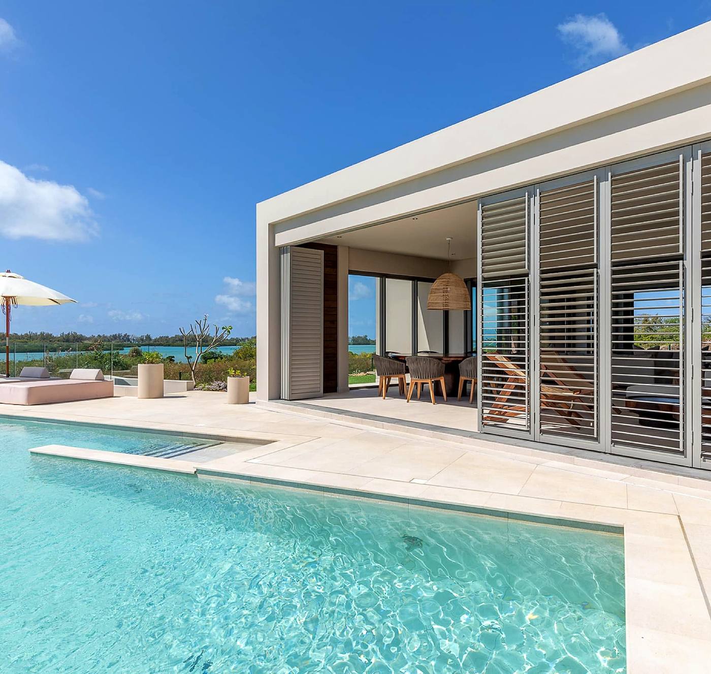 Grey aluminium louvre shutters on a poolside pavilion