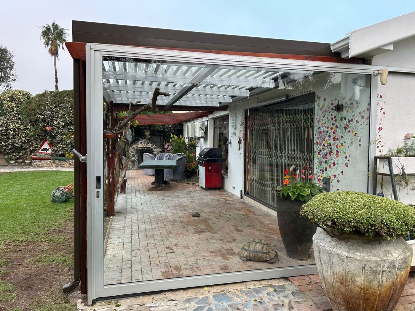 Bronze frame, white blades aluminium louvre roof over a patio in Table View, Cape Town.
