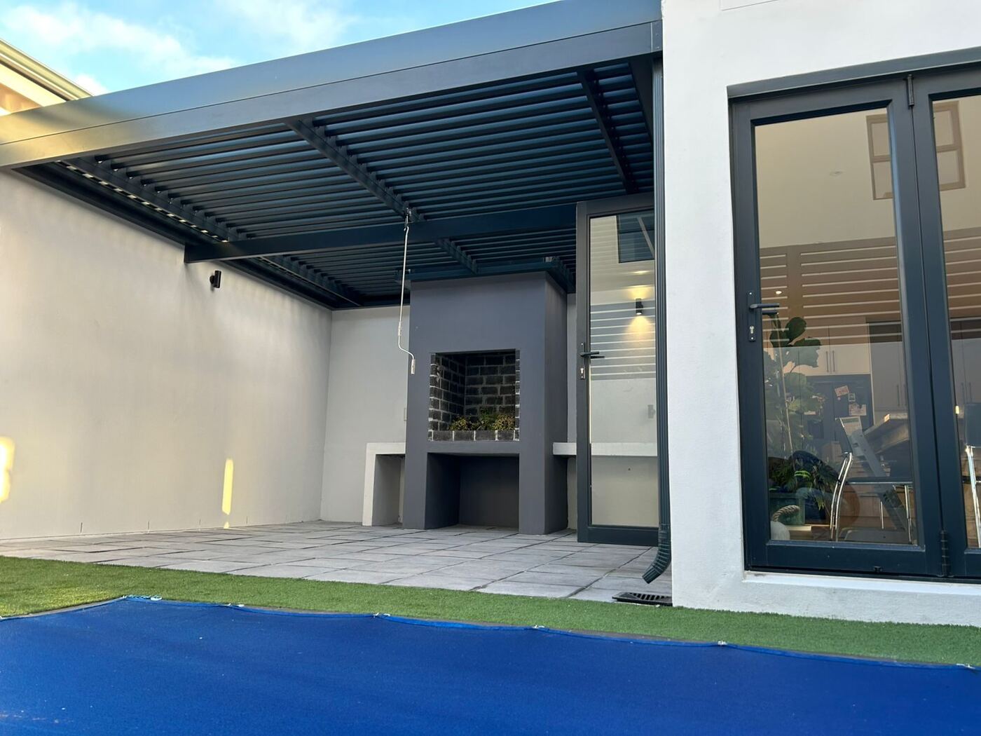 Charcoal frame & blades aluminium louvre awning over a patio in Noordhoek, Cape Town.