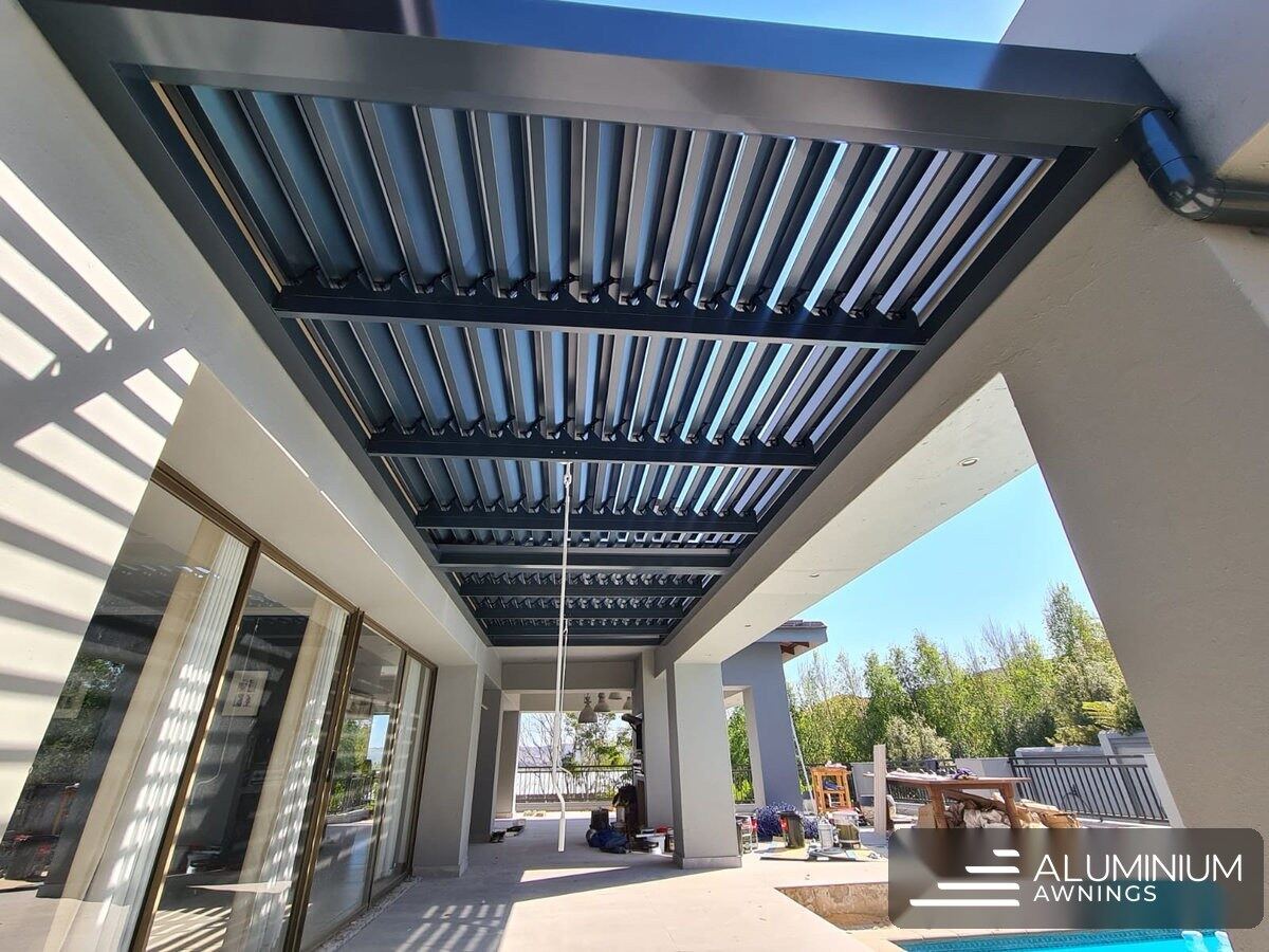Charcoal louvre roof over the Stellenbosch pool walkway with blades open to the sky.