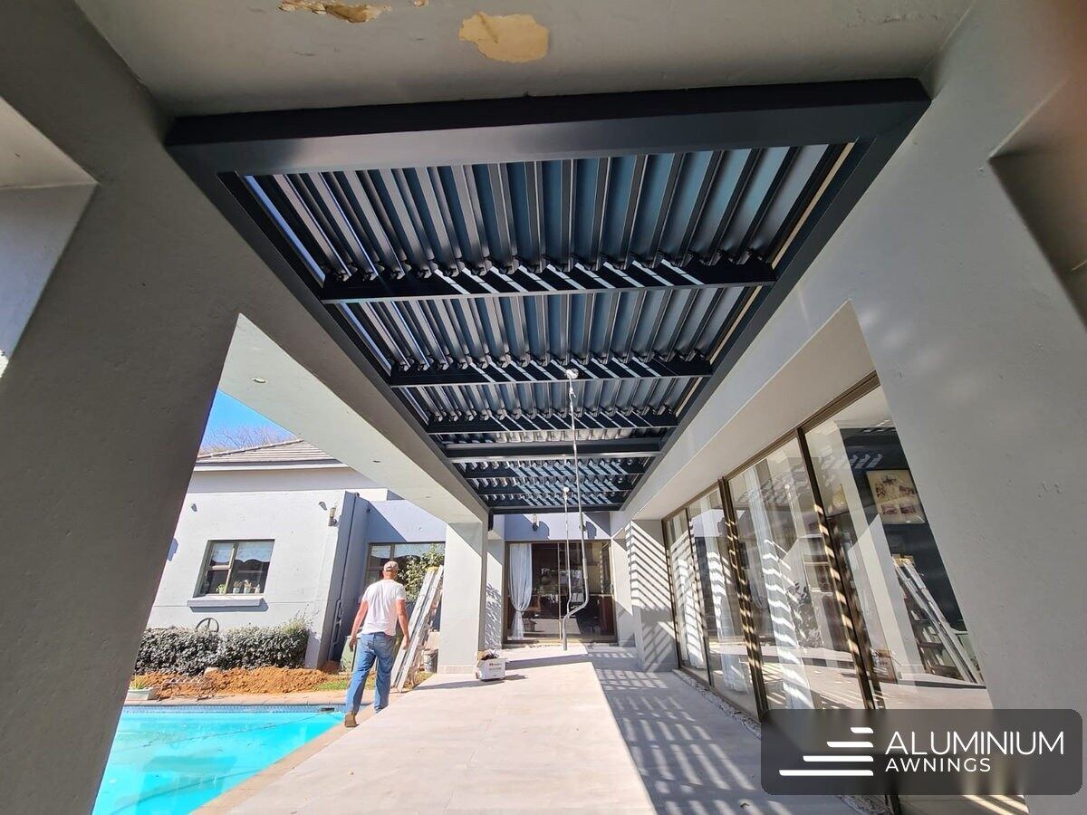 Charcoal aluminium louvre roof between the roof sections at the Stellenbosch home, blades half-open.