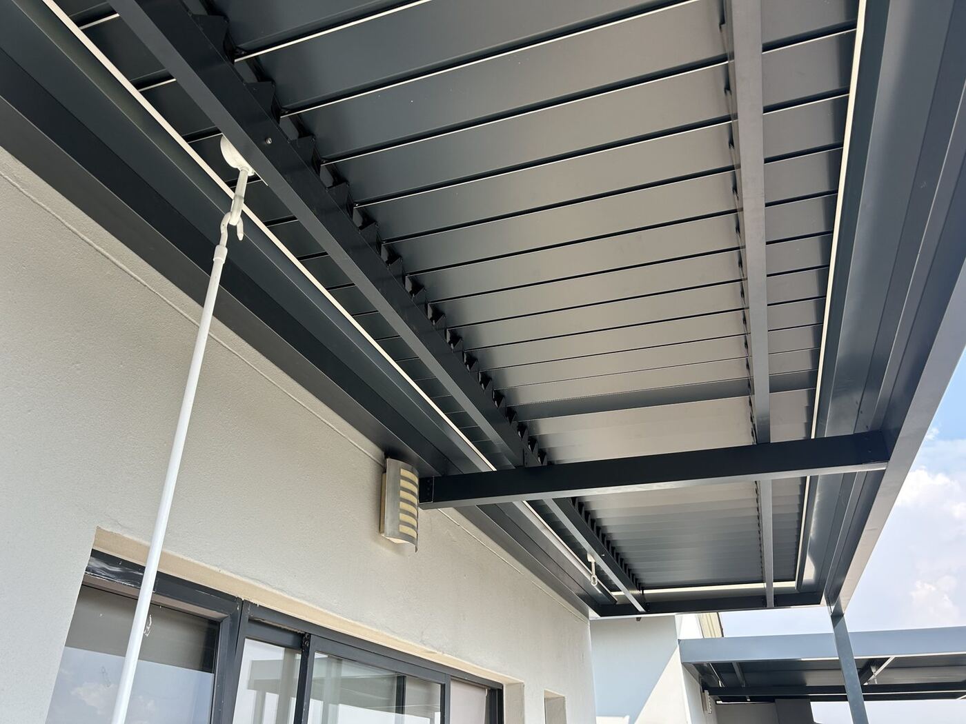 Charcoal-framed aluminium louvre roof with a white louvre top over a patio in Somerset West, Cape Winelands.