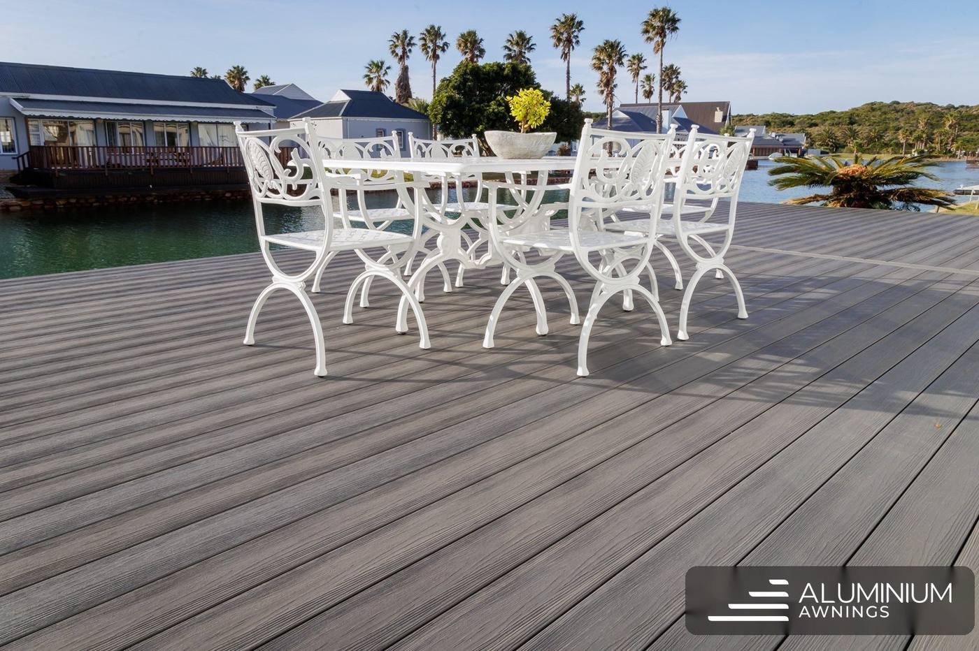 Driftwood-grey composite deck with outdoor dining beside the water