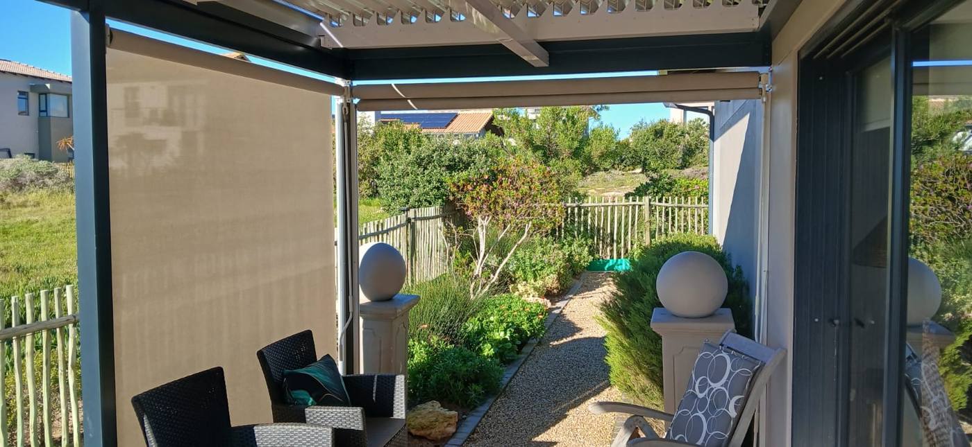 Taupe drop awning on a louvre awning beside a garden