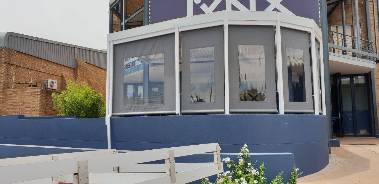 Grey drop blinds with clear panels around a venue terrace
