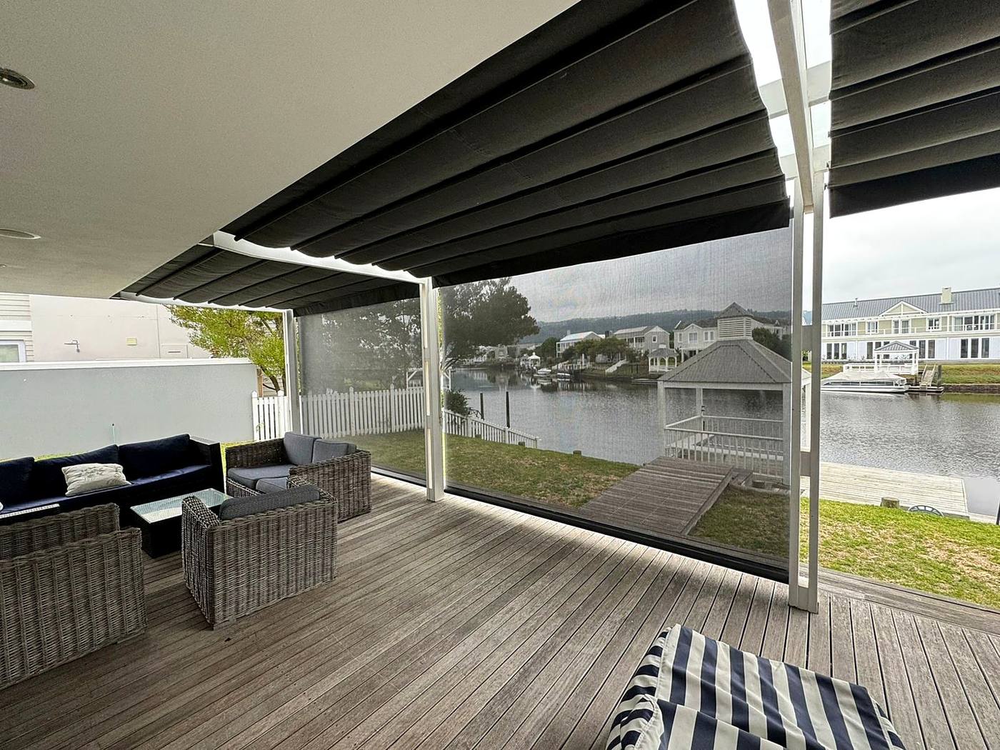 Charcoal drop screens lowered around a covered timber deck on the water