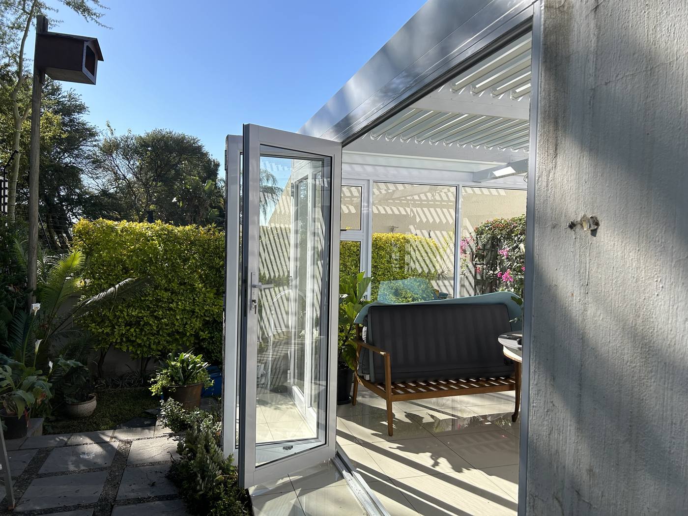 Enclosed patio glazing looking onto a clipped garden in Constantia