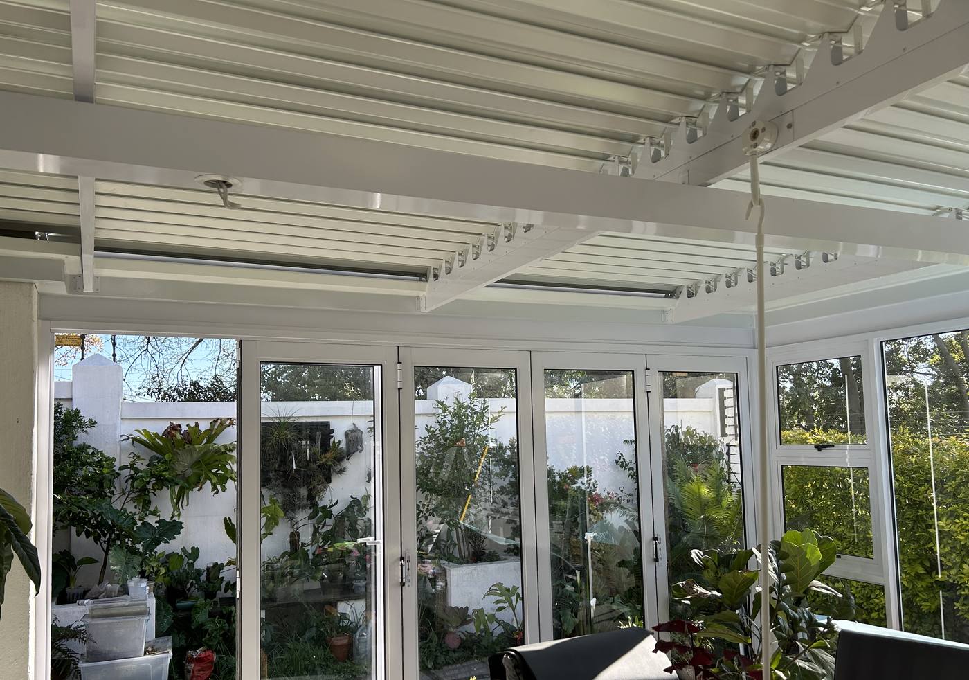 Adjustable white louvre blades over an enclosed Constantia patio