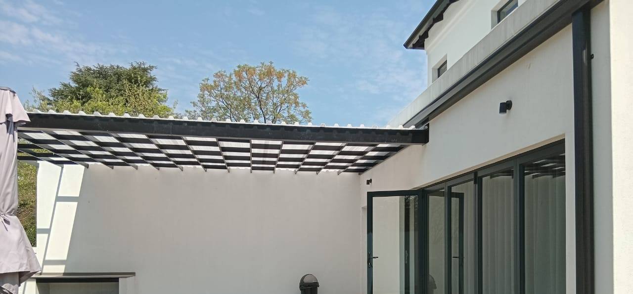 Clear polycarbonate roof on a black frame over a walled courtyard