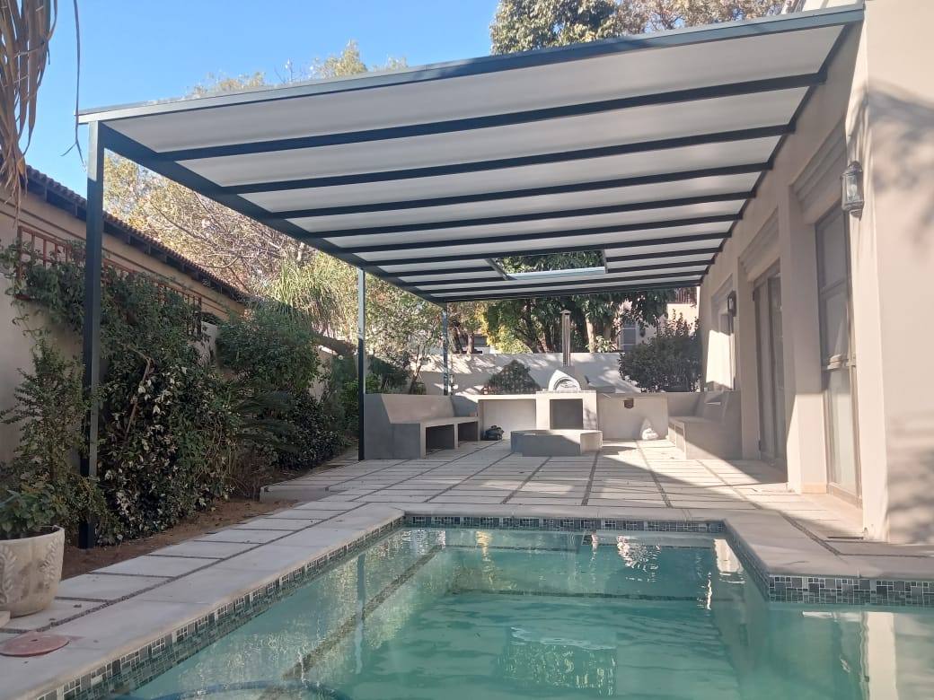 Aluminium pergola with a polycarbonate roof over a pool patio