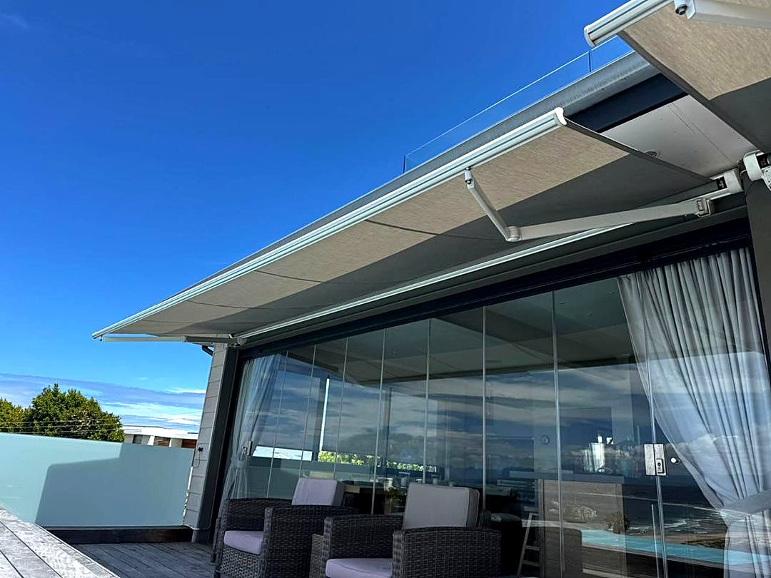 Retractable awning extended over a glass-fronted coastal terrace